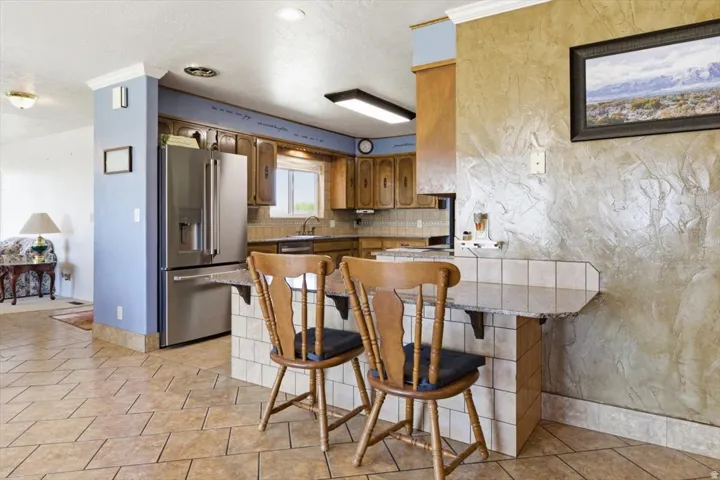 Kitchen featuring a stainless steel refrigerator, wood cabinetry, and a tile backsplash