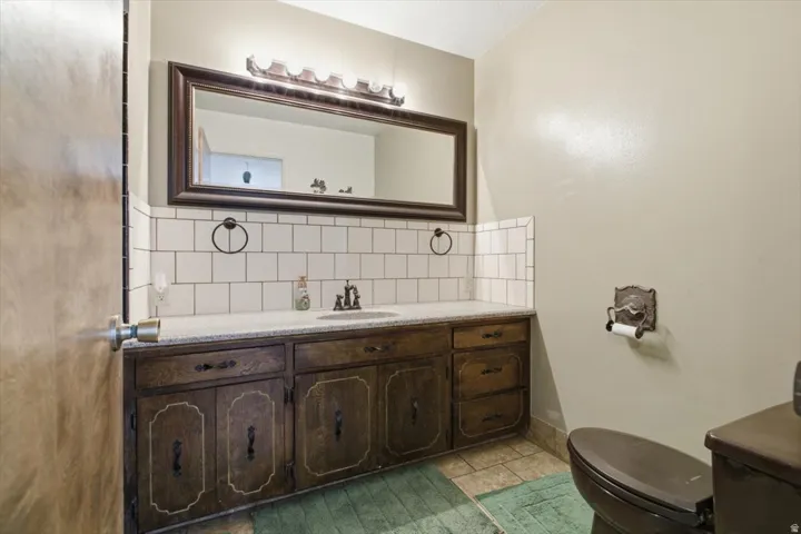 Wood-finish vanity with ample storage, a granite-finish countertop, and an undermount sink