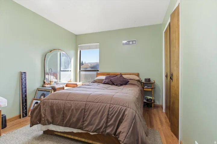 Bedroom featuring wood-finish flooring, light green painted walls, and a large window