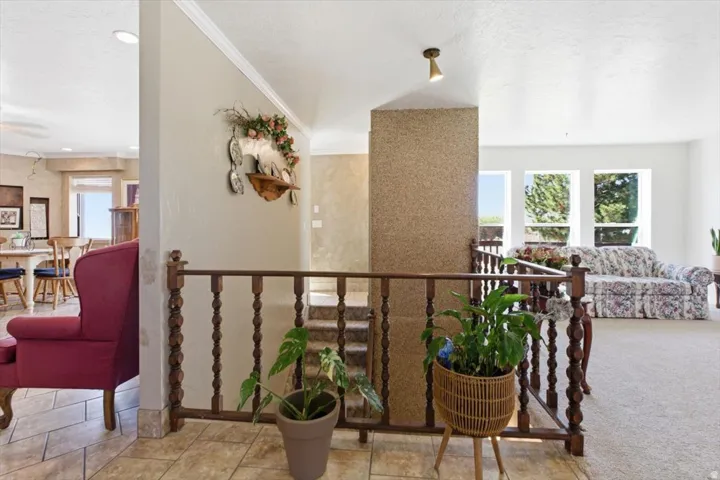 Tiled entryway with a wood spindle railing, leading to a carpeted living space with multiple windows