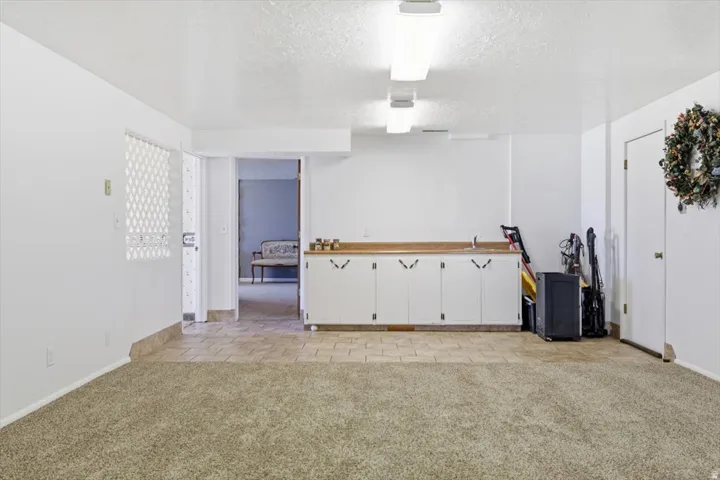 Spacious room featuring carpet flooring in the foreground and tile flooring in the background