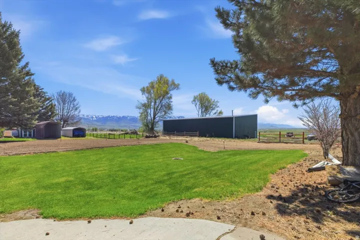 Expansive property featuring a manicured lawn area, a large metal barn, and two additional storage sheds