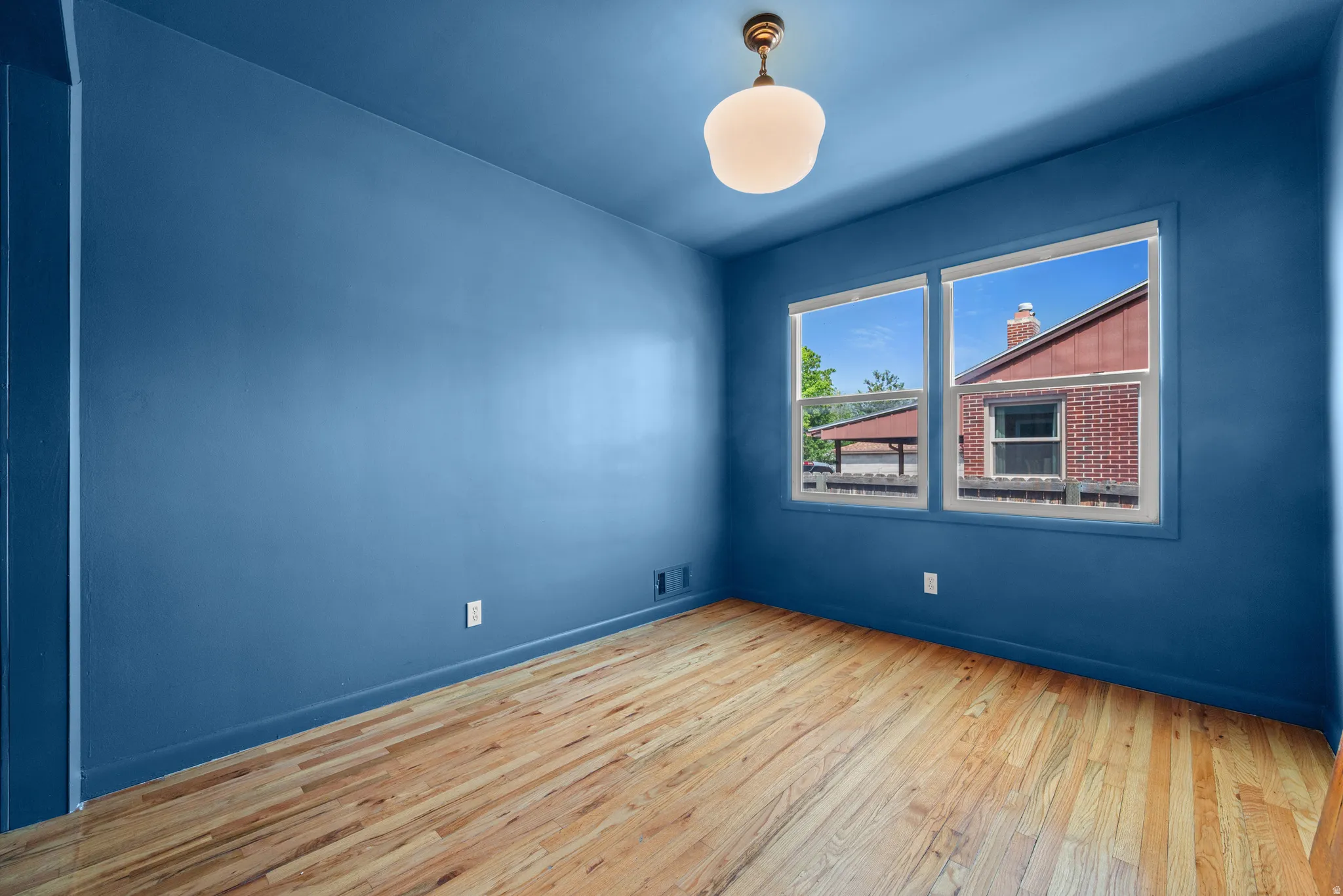 Room featuring wood-finish flooring, a pair of windows, and a flush-mount ceiling light fixture