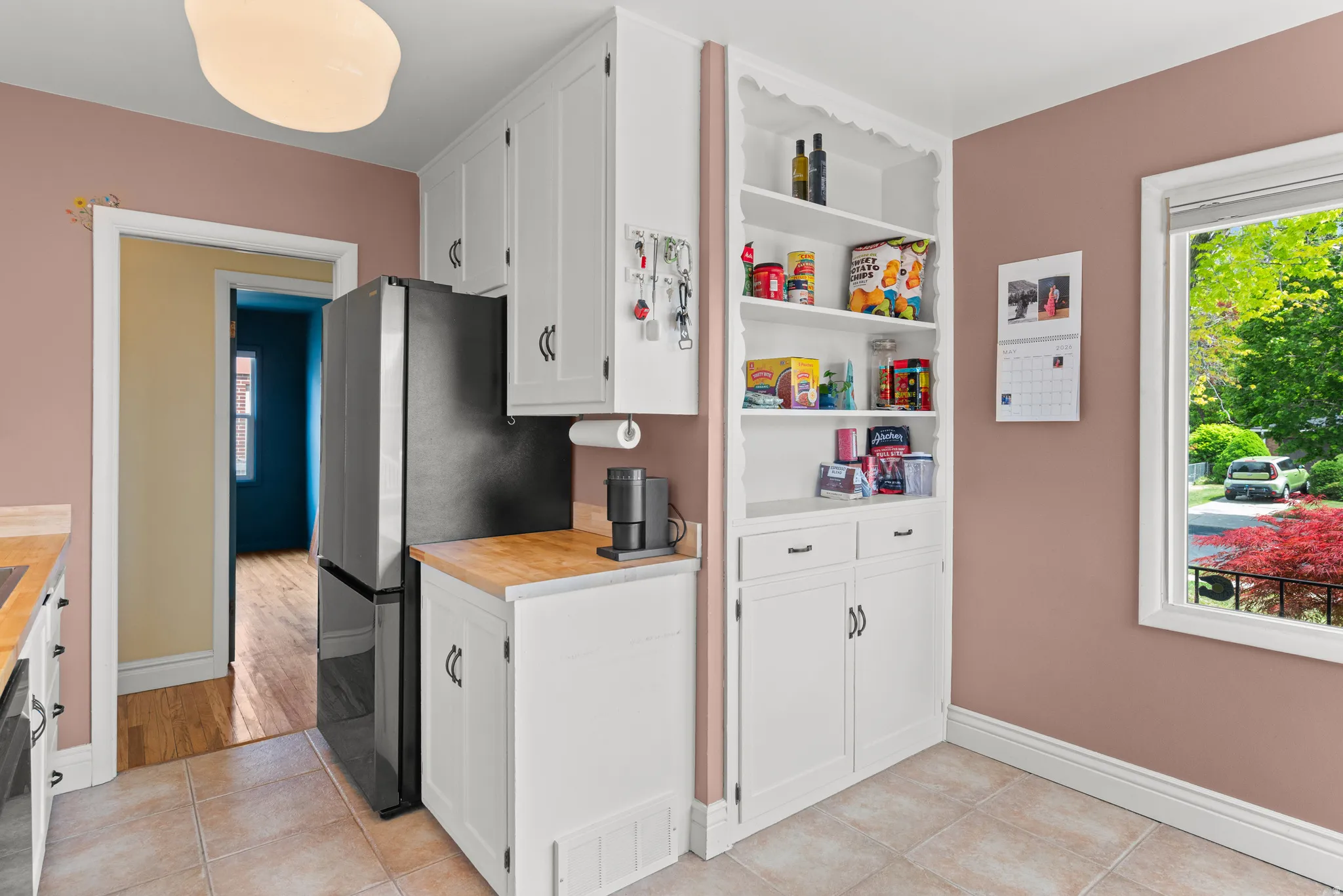 Kitchen featuring white cabinetry with dark hardware, butcher block countertops, and neutral tile flooring