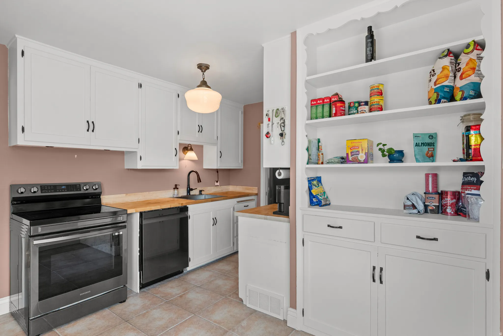Kitchen featuring white cabinetry, light wood-finish countertops, and a full suite of appliances including a black range and dishwasher