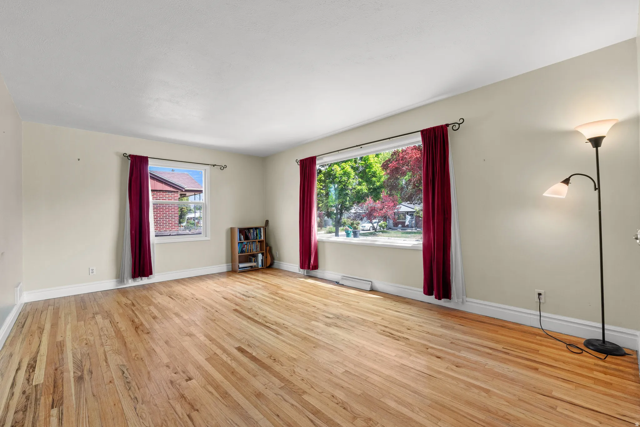 Spacious room featuring light-toned walls, wood-finish flooring, and white trim
