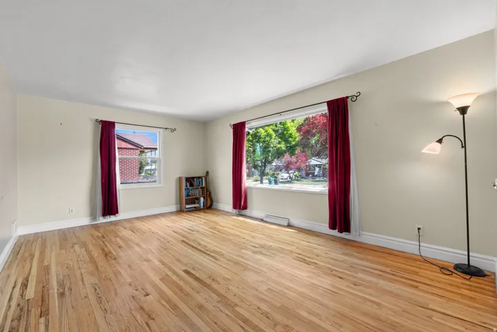 Spacious room featuring light-toned walls, wood-finish flooring, and white trim