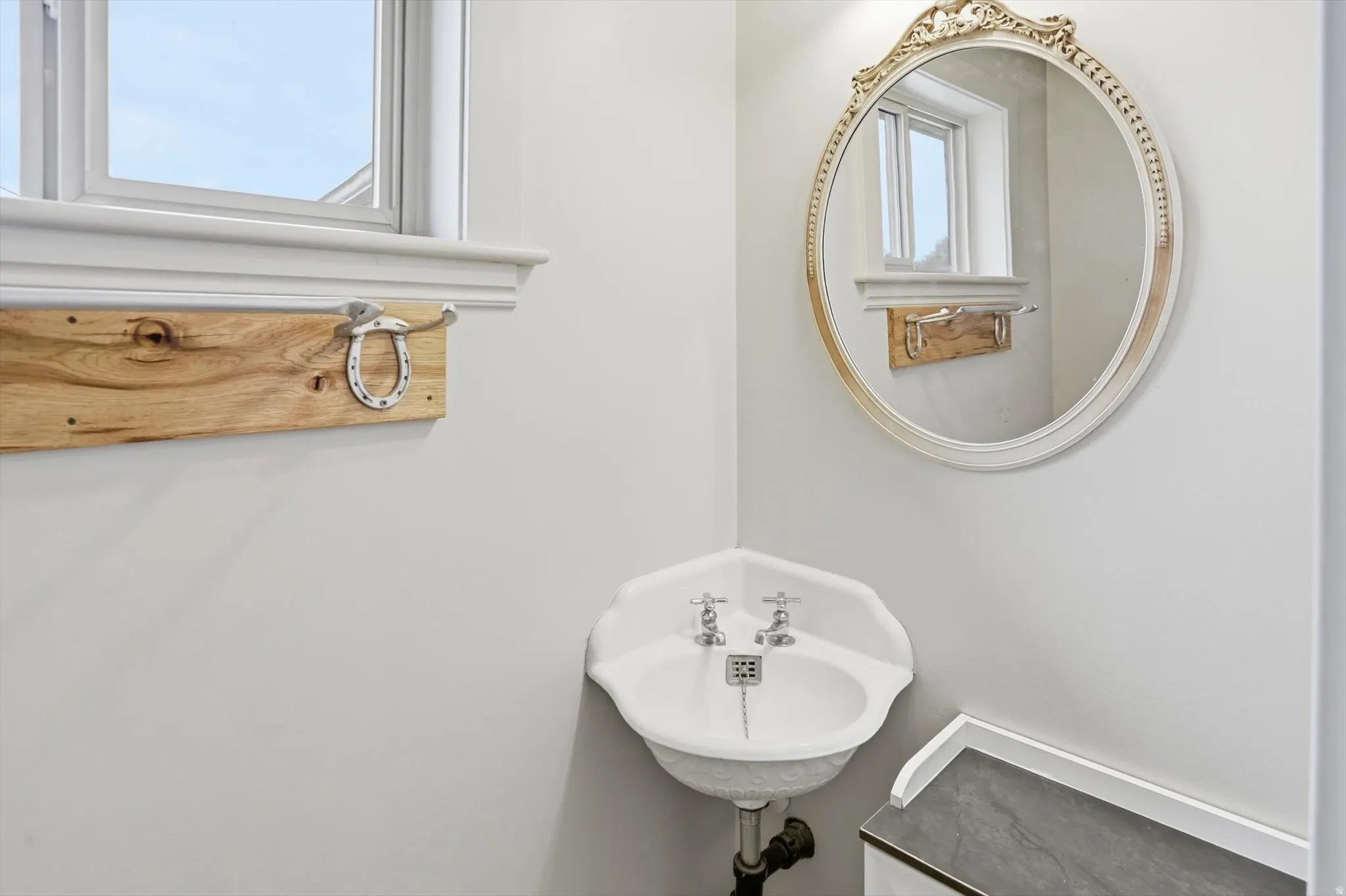 Corner pedestal sink with dual chrome faucets and a polished metal drain