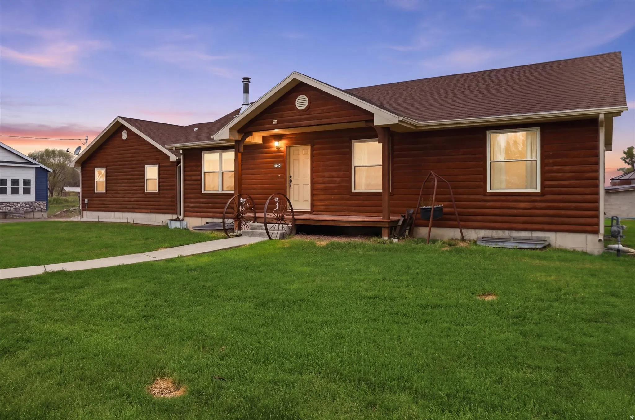 Wood-paneled home with a covered front porch, asphalt shingle roof, and a concrete pathway
