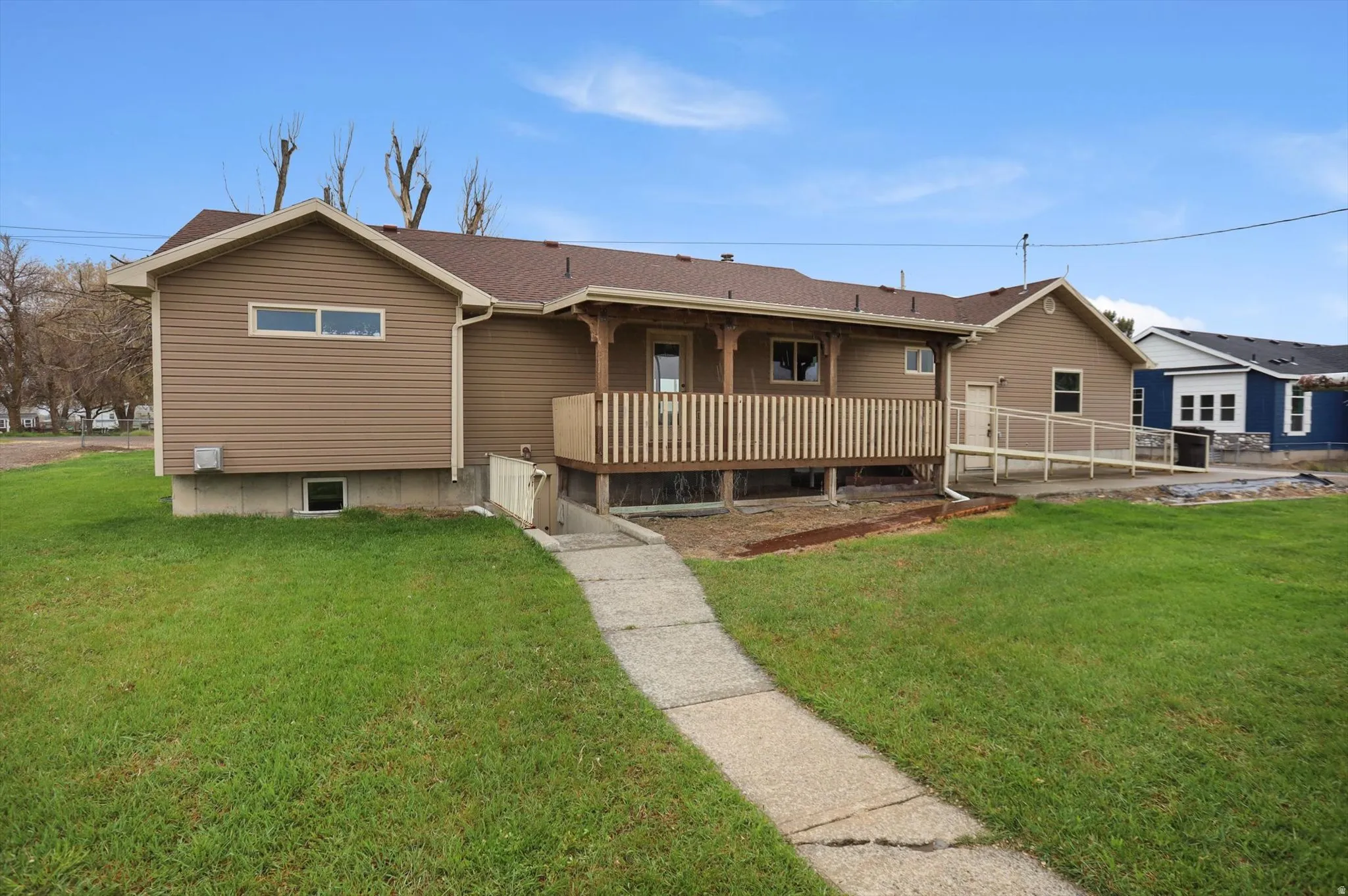 Exterior showcasing a covered porch, wood railing, and a concrete accessibility ramp