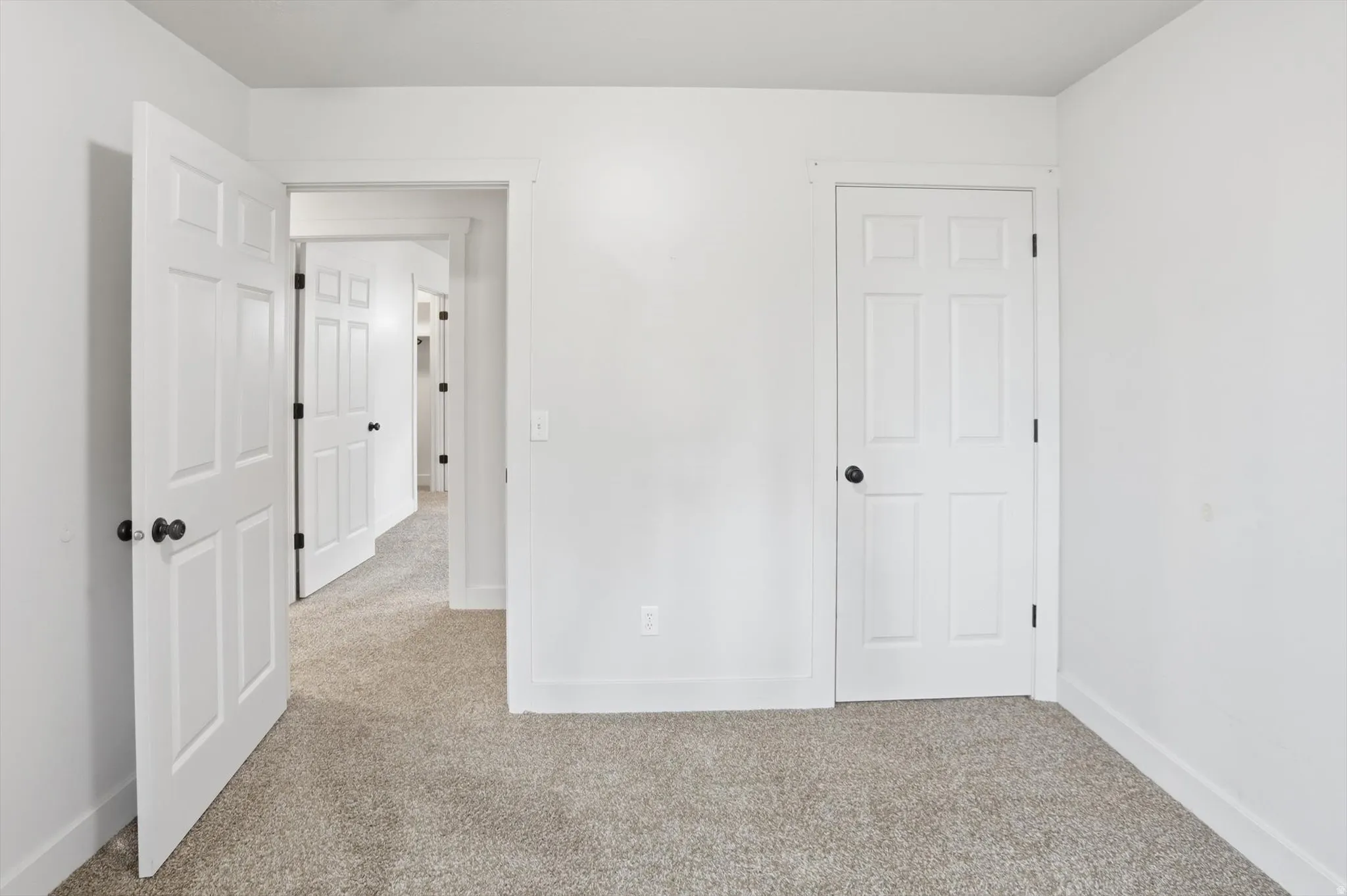 Neutral-toned carpeting extends throughout the space, complemented by crisp white walls and white trim