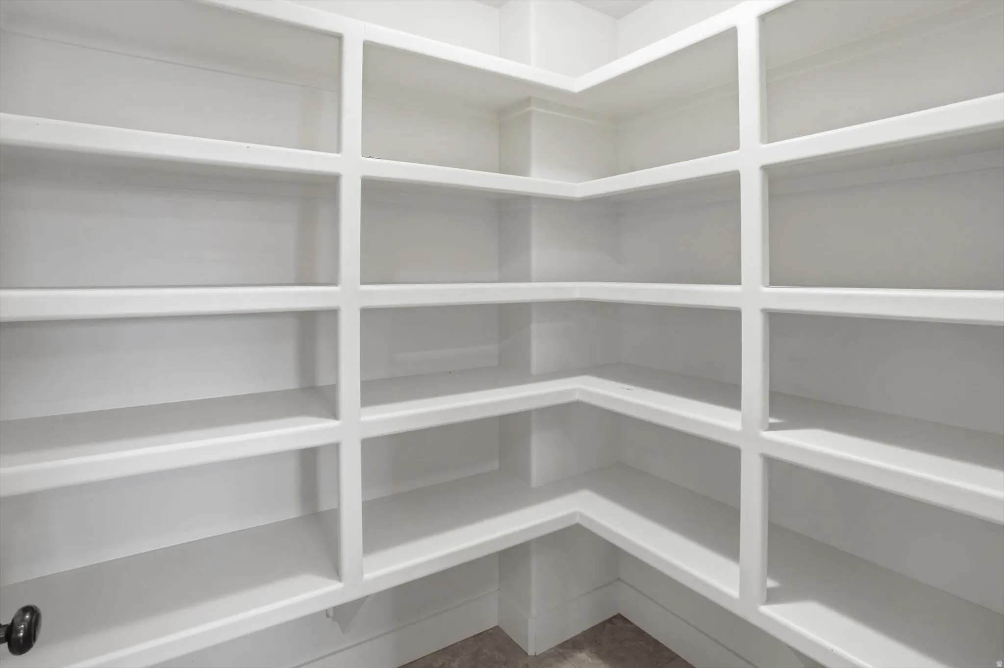 Spacious corner pantry featuring built-in white shelving, multiple tiers, and durable construction