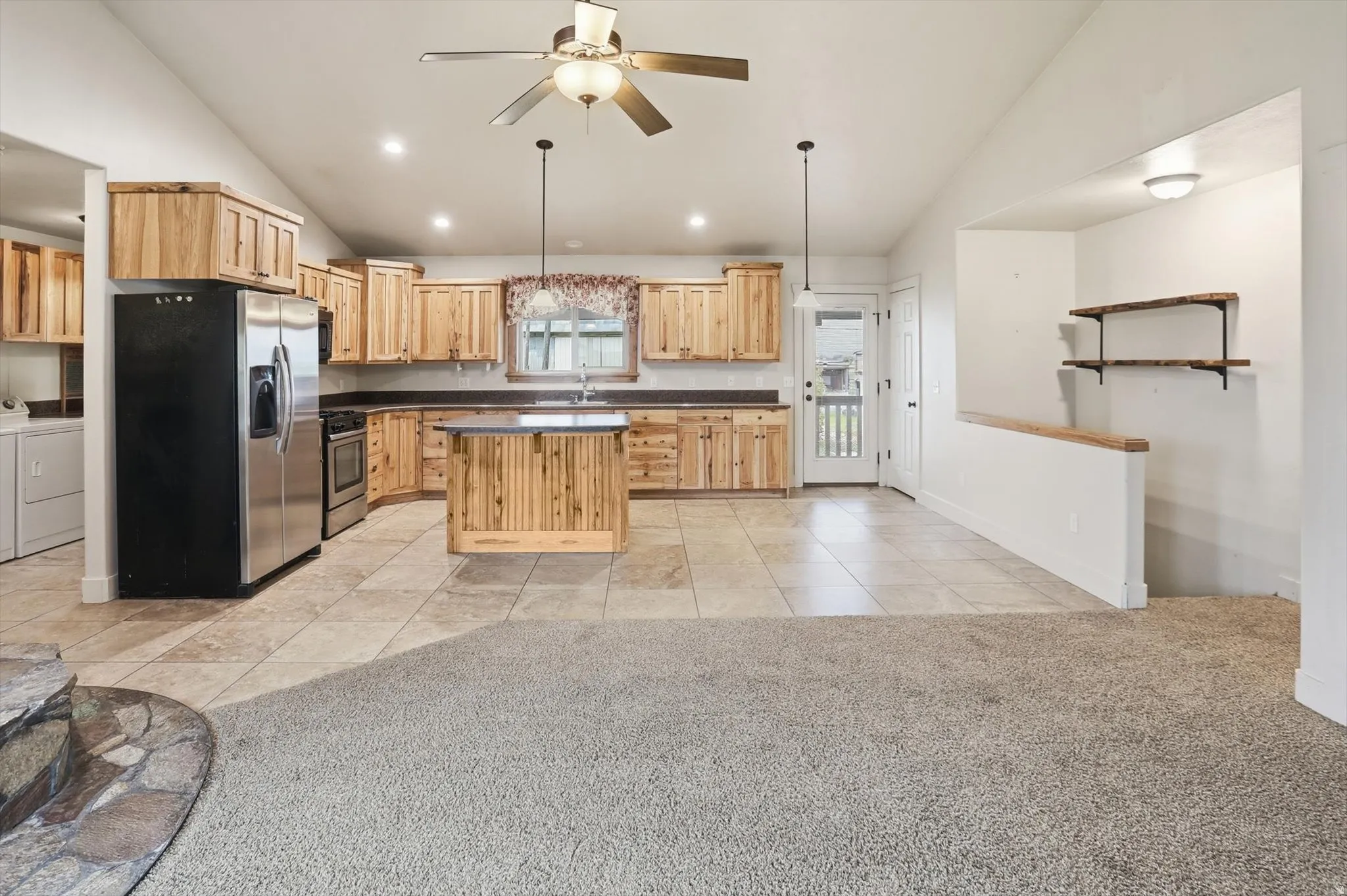 Vaulted ceilings above a kitchen featuring wood cabinetry, stainless steel appliances, and a central island