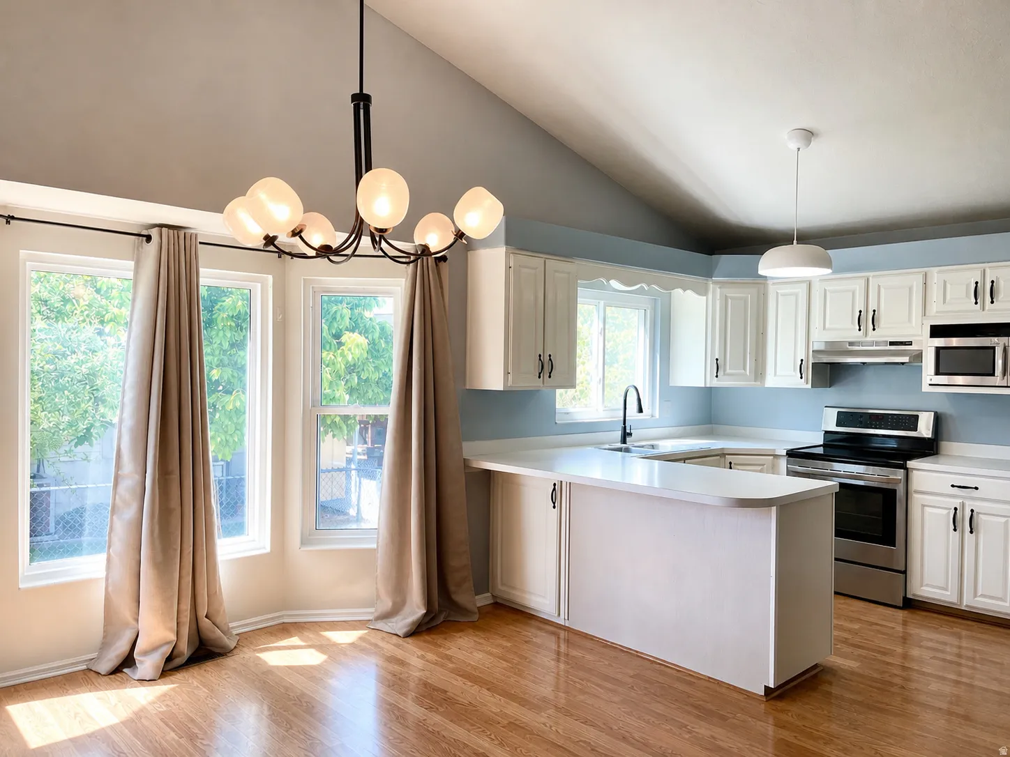 Kitchen with light countertops, stainless steel appliances, white cabinetry, a peninsula, and light wood finished floors
