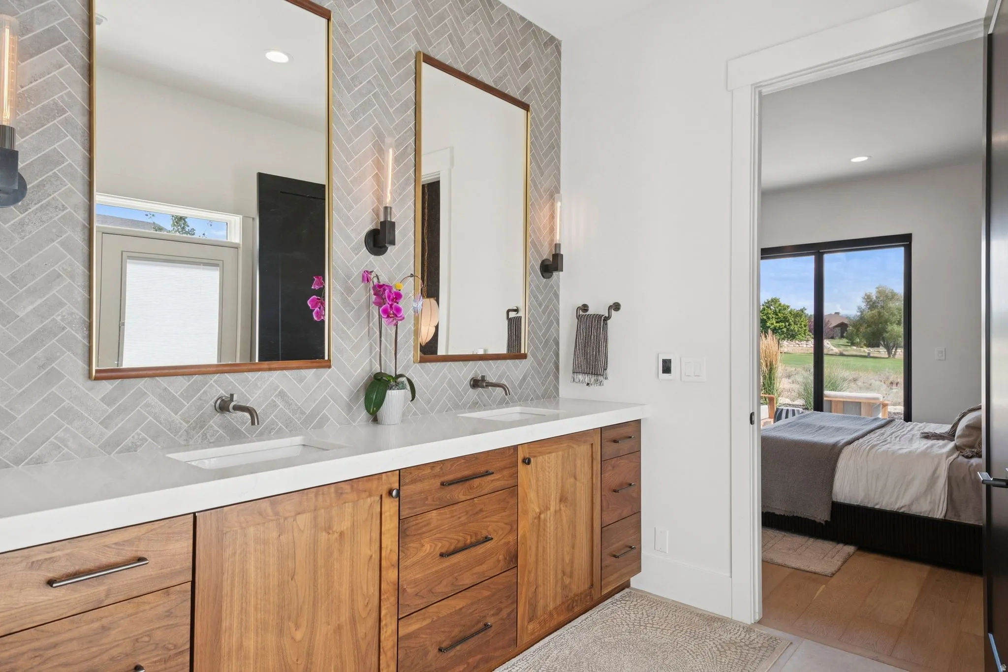 Dual vanity with walnut cabinetry and full-height tile backsplash with designer lighting. Steam shower and door that opens to outside hot tub.