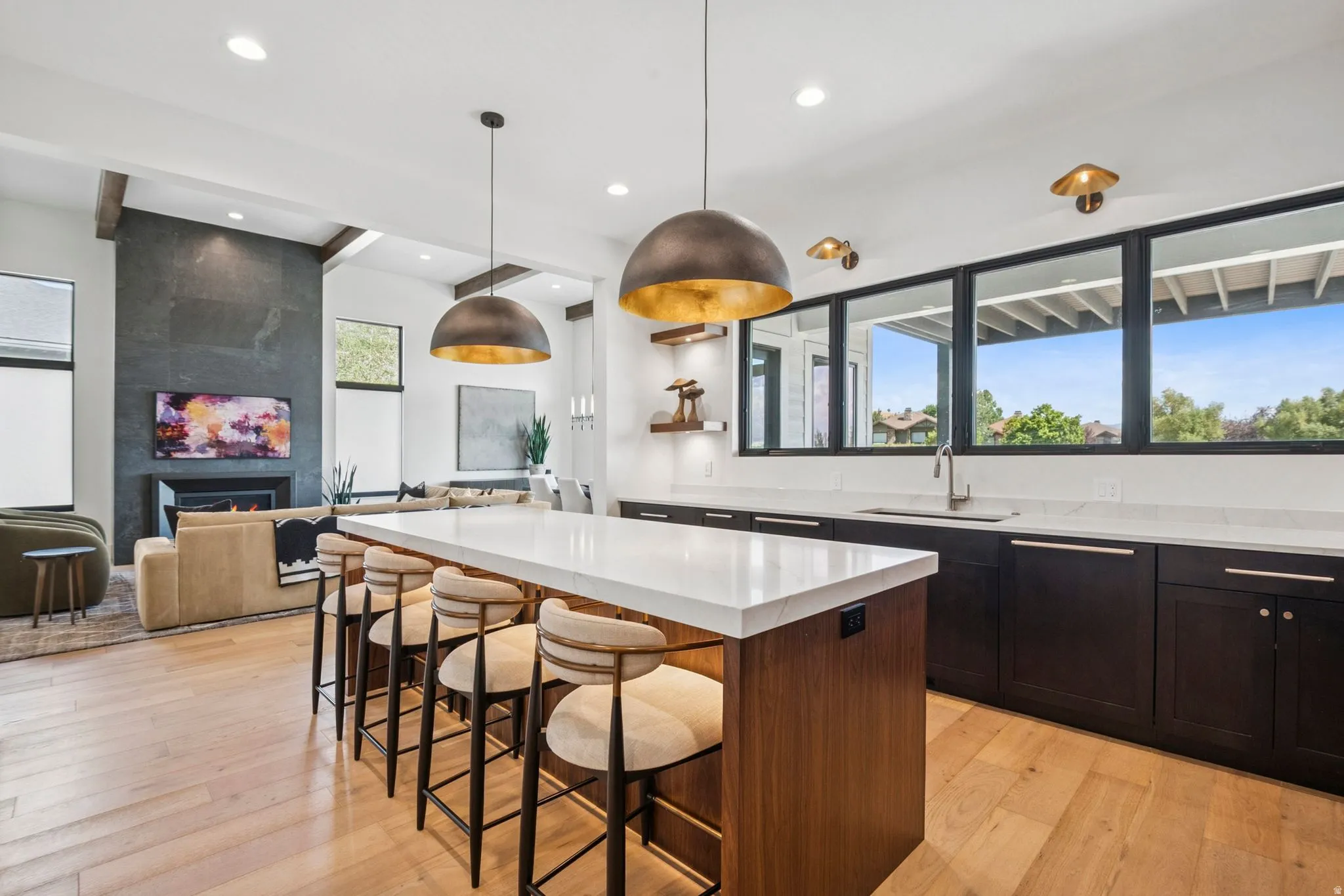 Spacious kitchen featuring a large island walnut cabinetry, and light hardwood flooring, designer lighting, with Wolf and Subzero appliances.