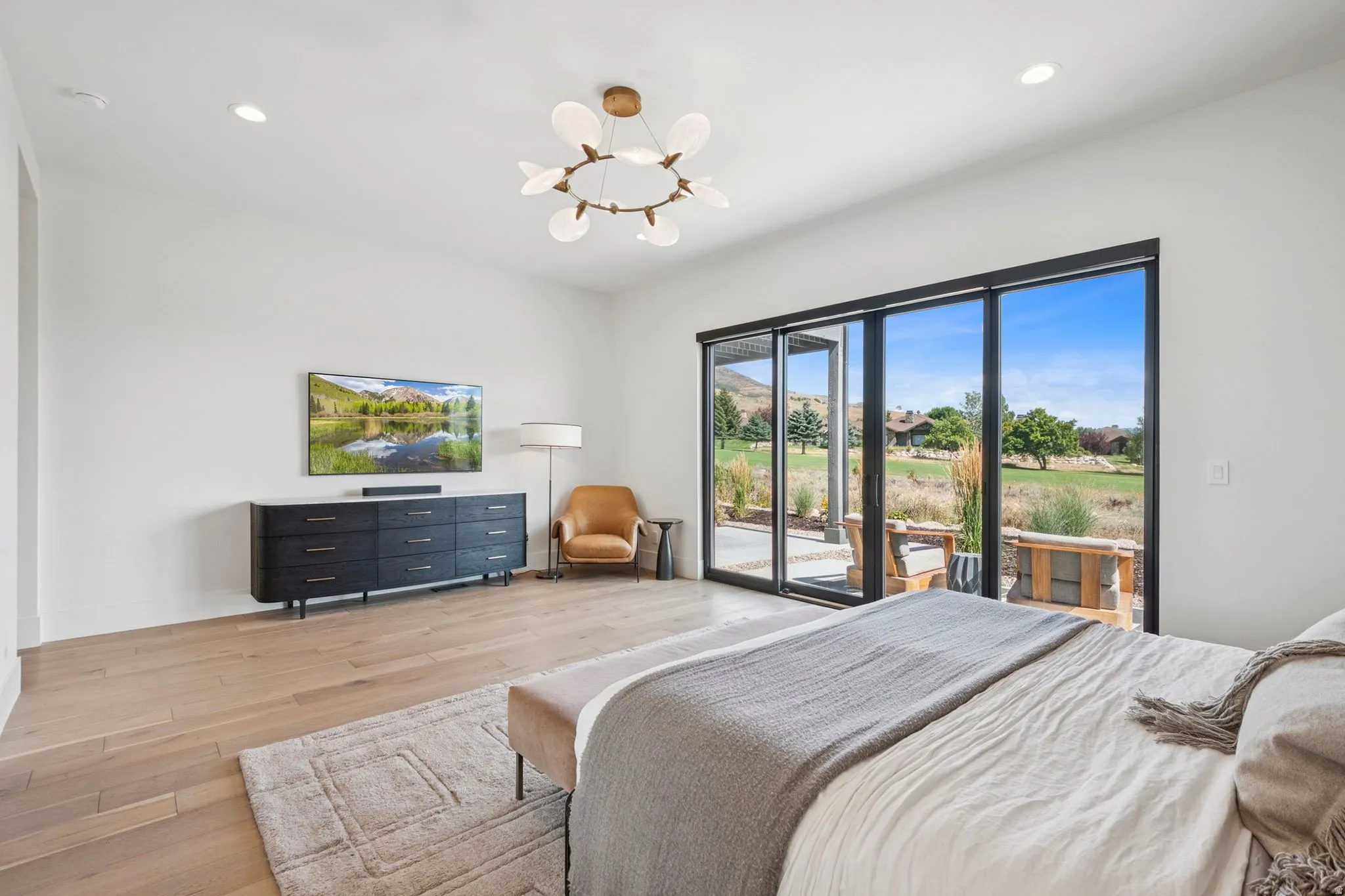 Extra large primary suite with floor-to-ceiling multi-panel glass doors that open to a patio area. Designer lighting and wallpaper for added luxury.
