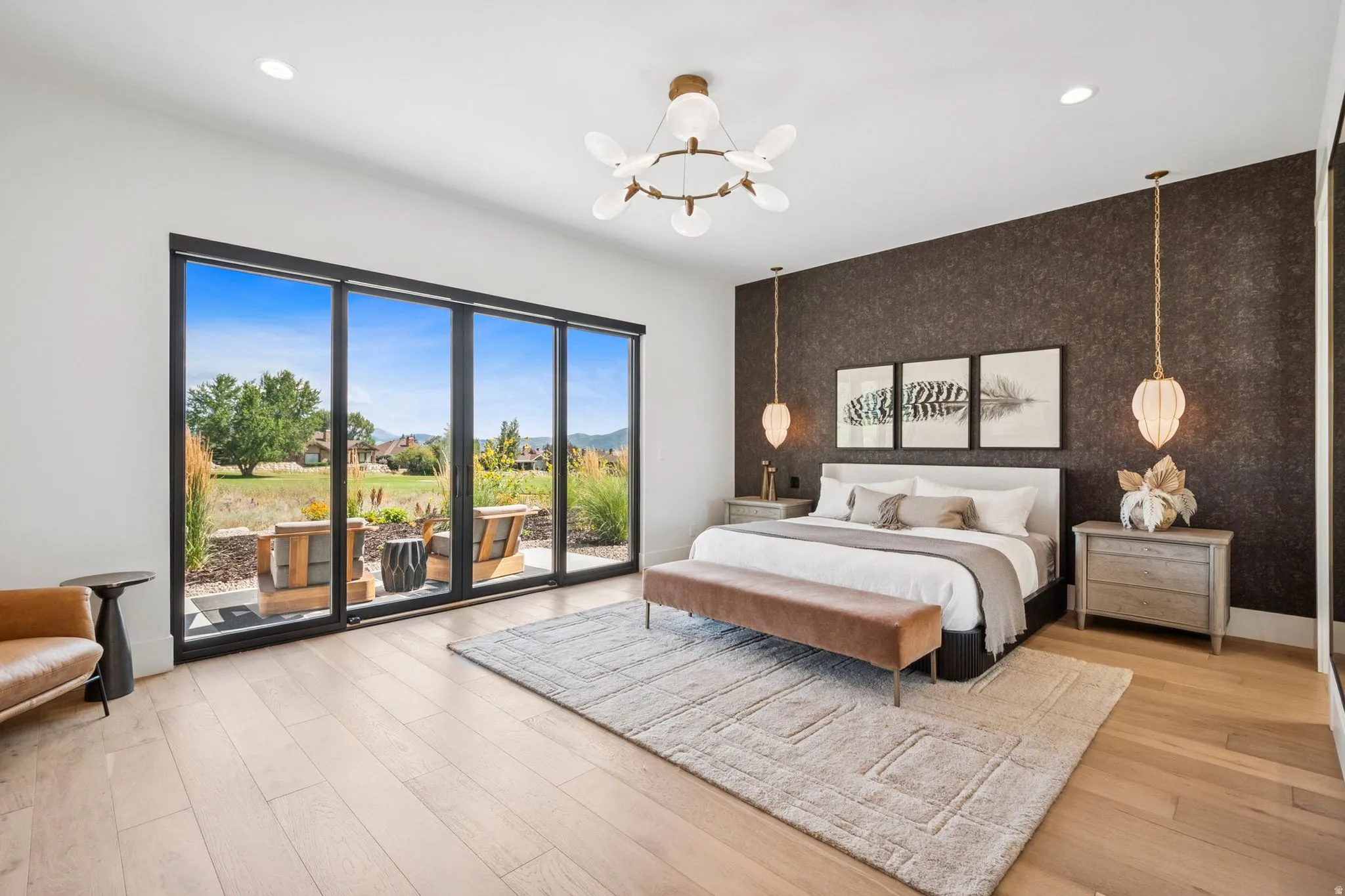 Extra large primary suite with floor-to-ceiling multi-panel glass doors that open to a patio area. Designer lighting and wallpaper for added luxury.