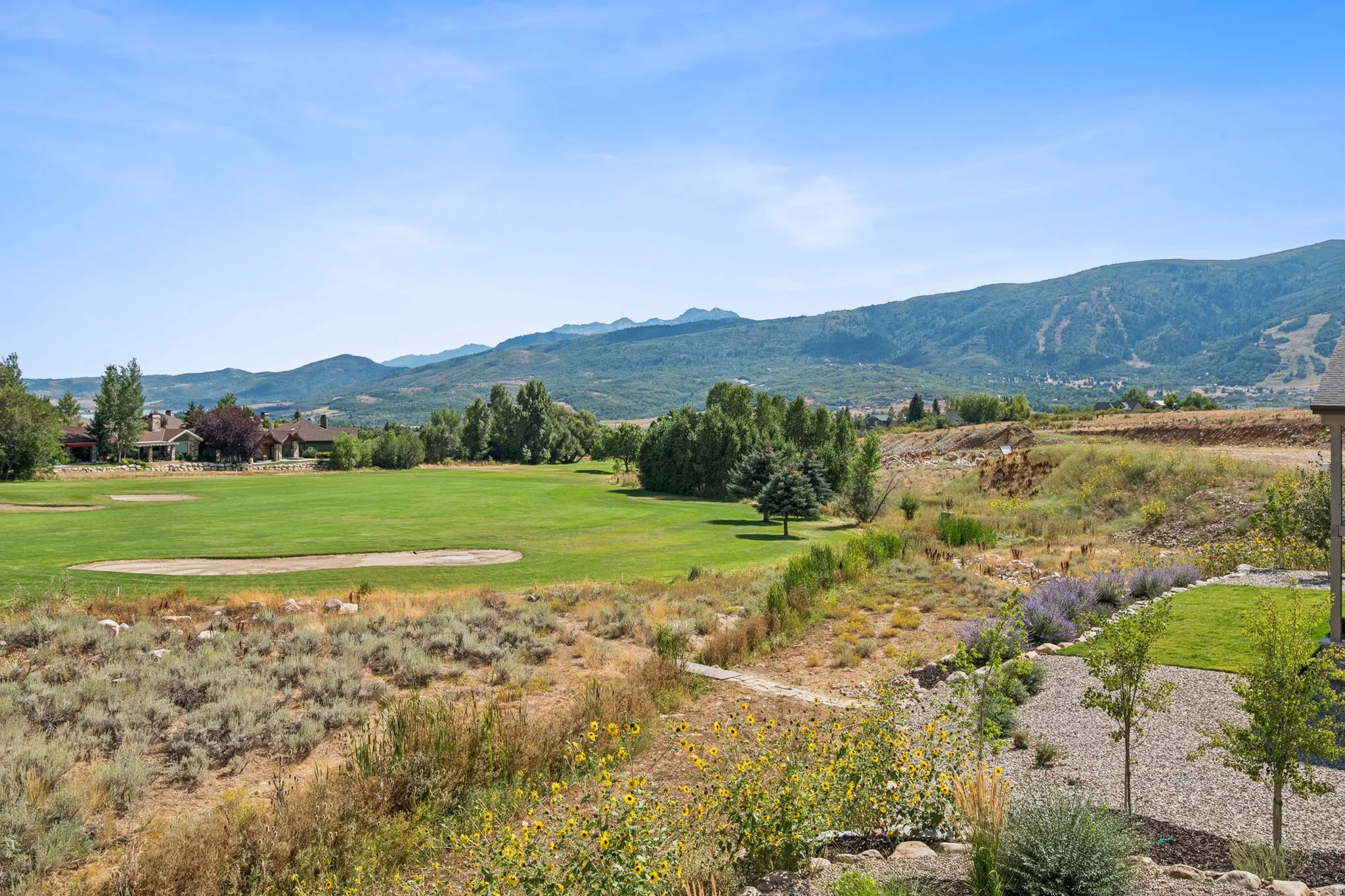 Expansive green space featuring a golf course, mountain backdrop, and distant ski slopes
