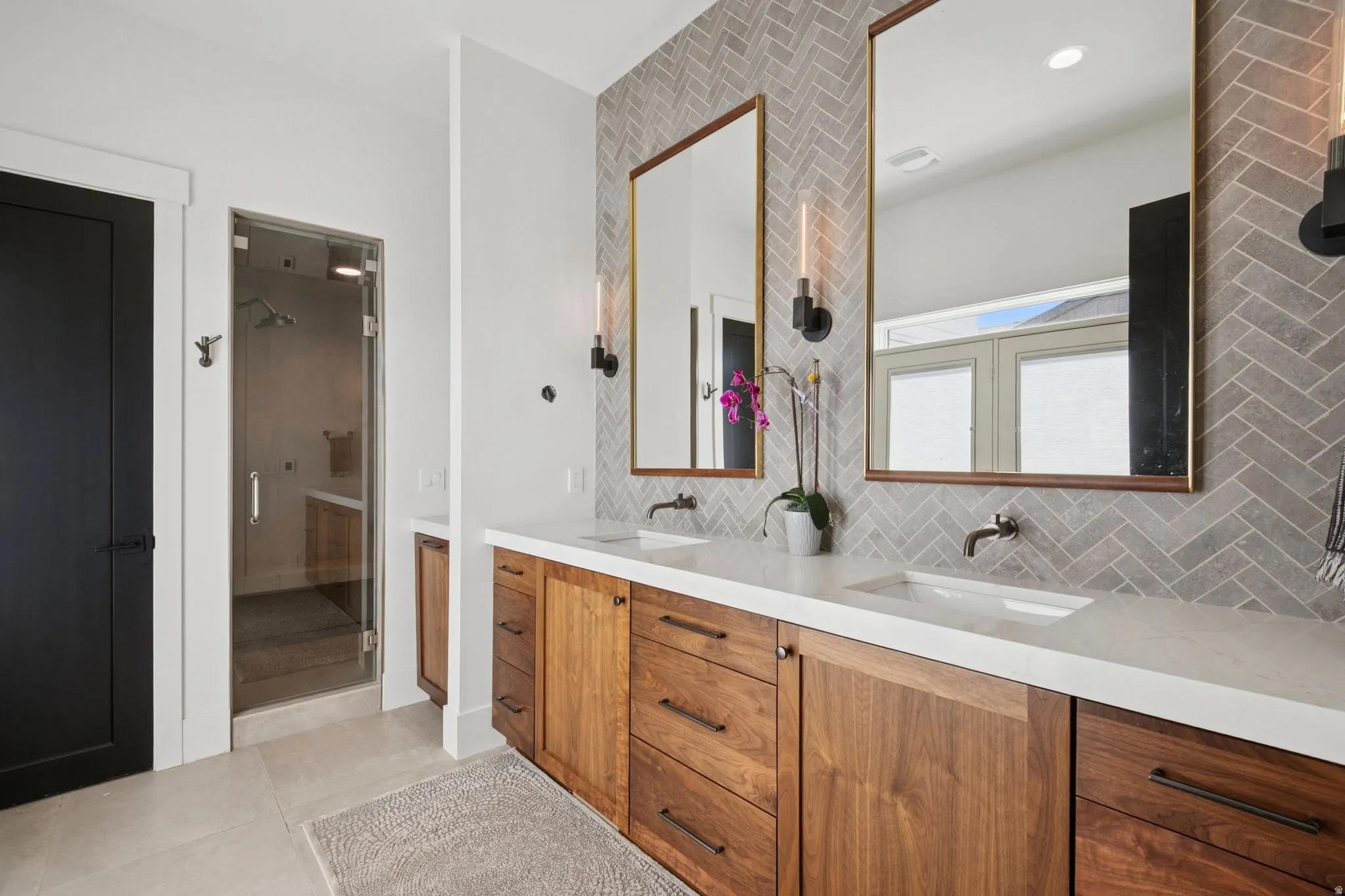 Dual vanity with walnut cabinetry and full-height tile backsplash with designer lighting. Steam shower and door that opens to outside hot tub.