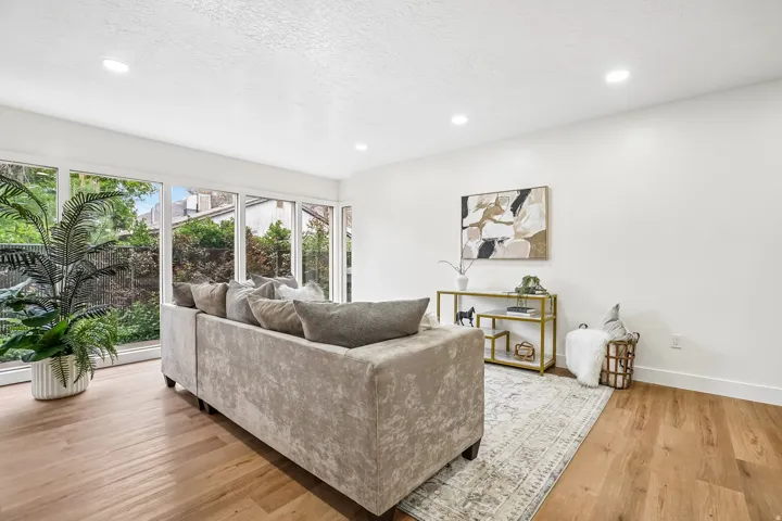Bright living space featuring large picture windows, wood-finish flooring, recessed lighting, and crisp white walls