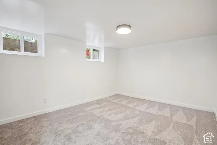 Room featuring light gray patterned carpeting, white painted walls, white baseboards, and two windows