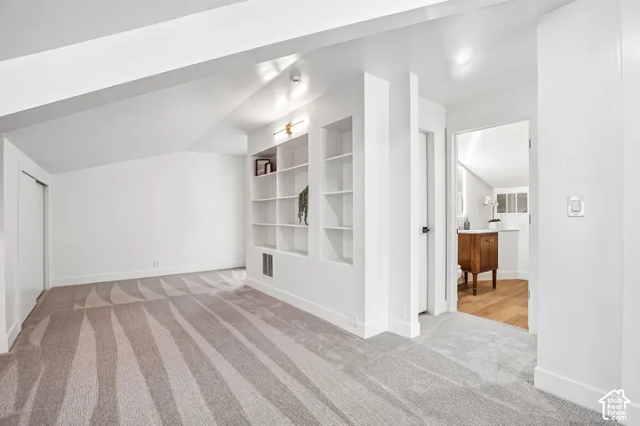 Carpeted room featuring a geometric pattern, built-in shelving, recessed lighting, and a closet with bifold doors