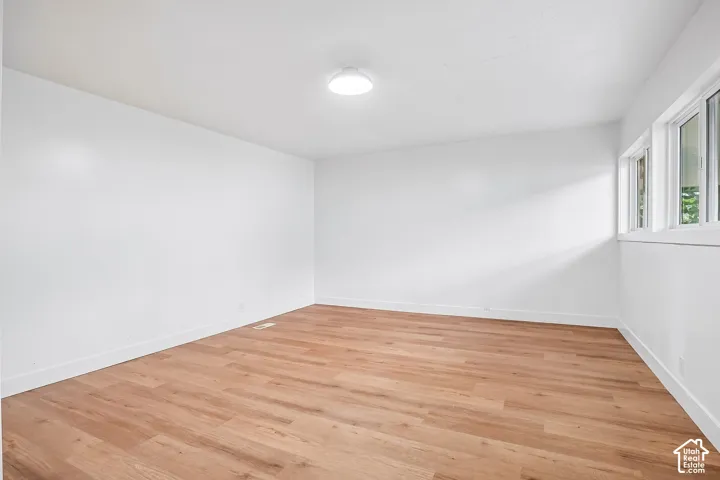 Spacious room featuring wood-finish flooring, white walls, and bright white trim