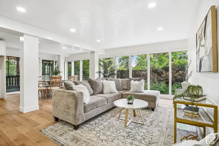 Expansive living area featuring wood-finish flooring, recessed lighting, and abundant natural light from numerous windows
