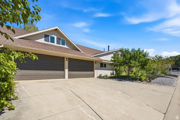 Dual garage doors with exterior lighting, concrete driveway, and dormer window
