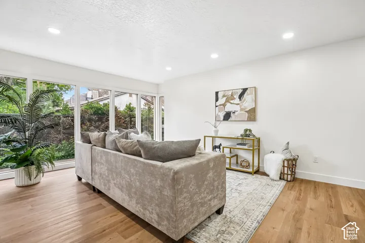 Bright living space featuring large picture windows, wood-finish flooring, recessed lighting, and crisp white walls