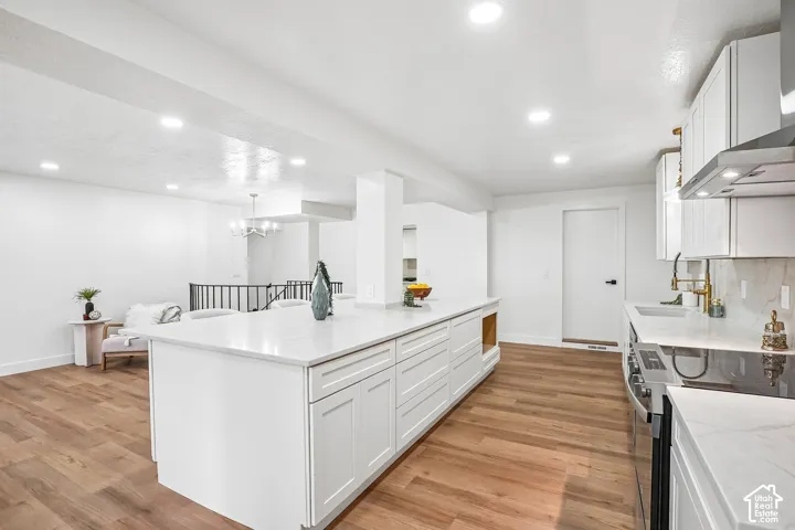 Spacious kitchen presenting a large central island with white cabinetry and light-toned countertops