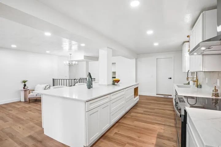 Spacious kitchen presenting a large central island with white cabinetry and light-toned countertops