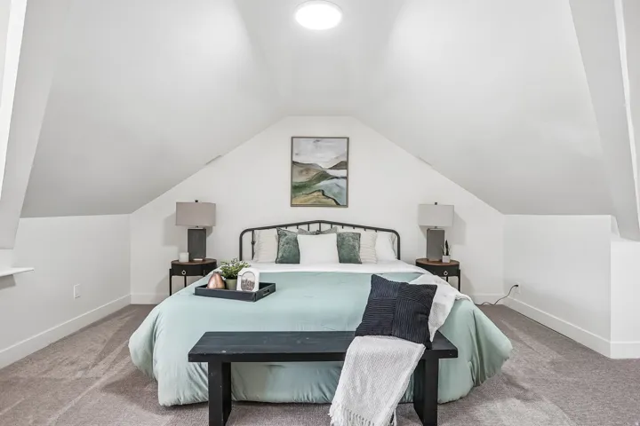 Room featuring an angled ceiling and neutral-toned carpeting