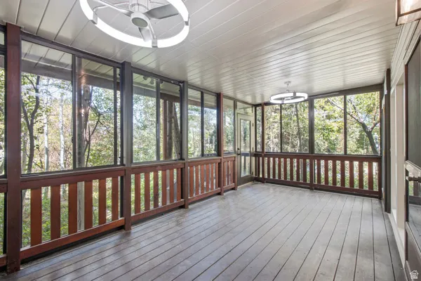 Screened porch with wood flooring, wood railing, and ceiling-mounted fans