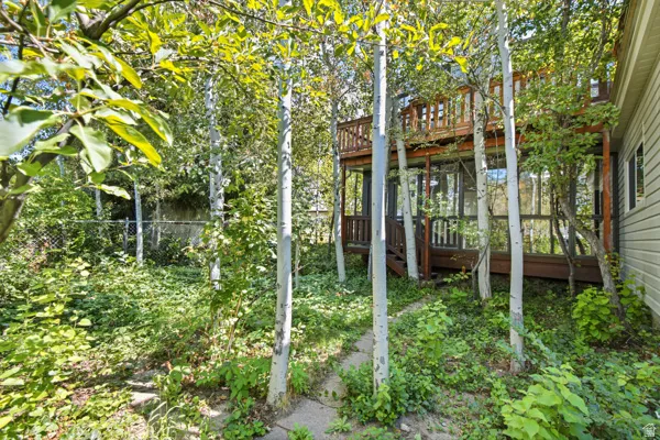 Multi-level wood deck with privacy railing, full-height windows, and mature trees