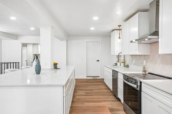 Modern kitchen featuring white cabinetry, light-toned countertops, and wood-finish flooring