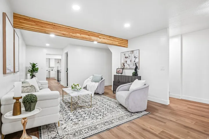White-painted living space featuring a prominent wood-finish ceiling beam, recessed lighting, wood-finish flooring, and crisp white baseboards