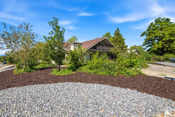Landscaped exterior featuring a gravel area, bark mulch, and mature plantings