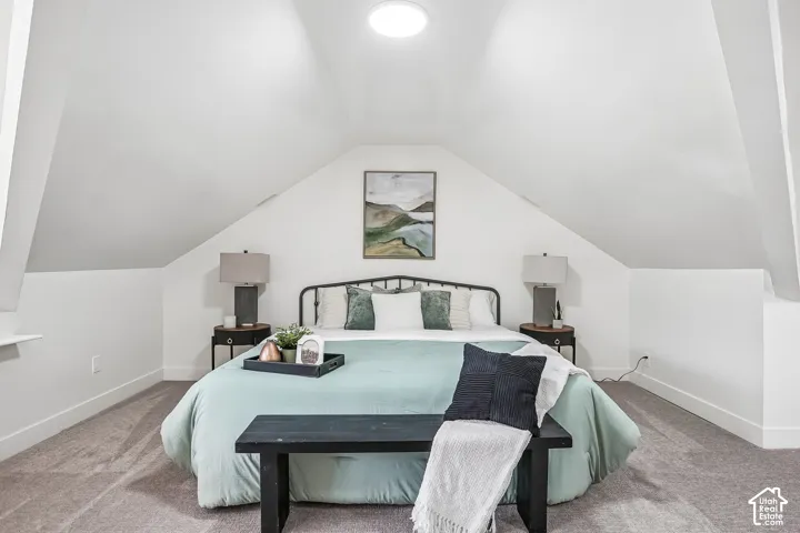Room featuring an angled ceiling and neutral-toned carpeting