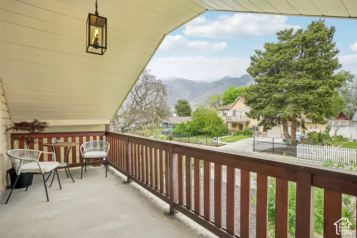 Covered balcony with wood railing, concrete flooring, and a black lantern-style pendant light