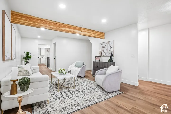White-painted living space featuring a prominent wood-finish ceiling beam, recessed lighting, wood-finish flooring, and crisp white baseboards