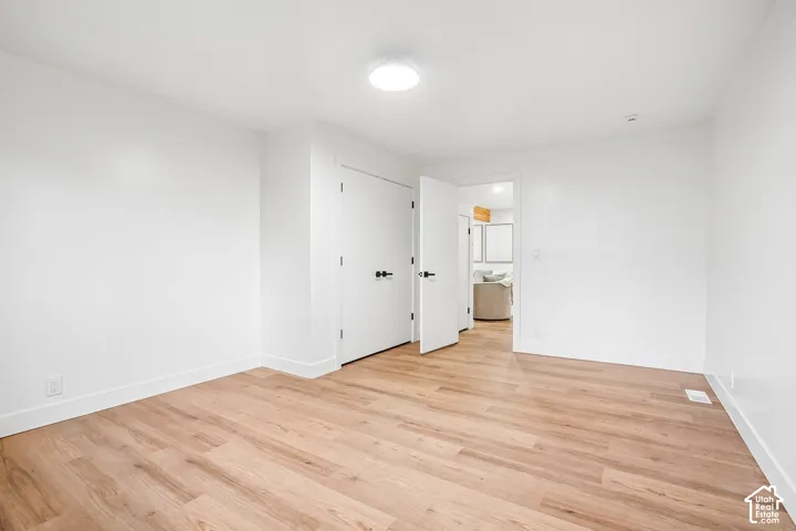 Bright room featuring wood-finish flooring, white painted walls, and white trim
