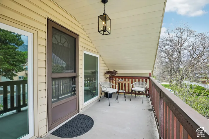 Covered outdoor balcony featuring tan siding and a dark brown door with an upper screen panel