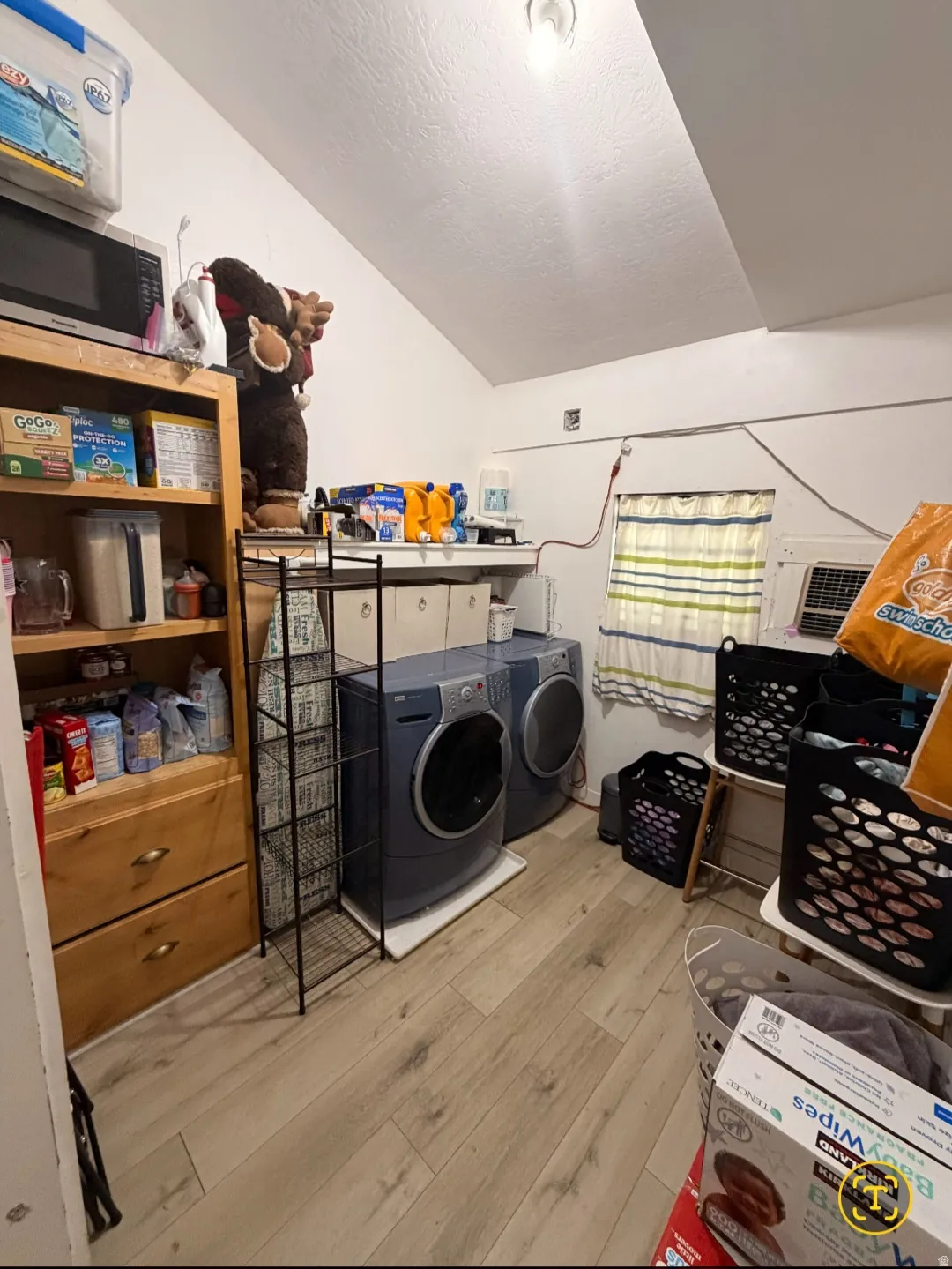 Dedicated utility space featuring wood-finish flooring and sloped ceiling