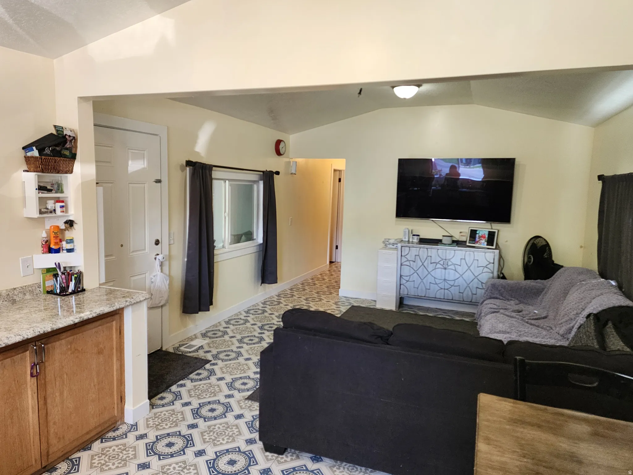 Open-concept living area with vaulted ceilings and patterned floor tile