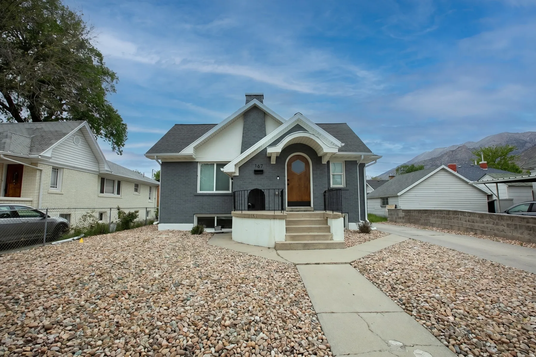 View of front of house featuring brick siding, a chimney, roof with shingles, and a mountain view