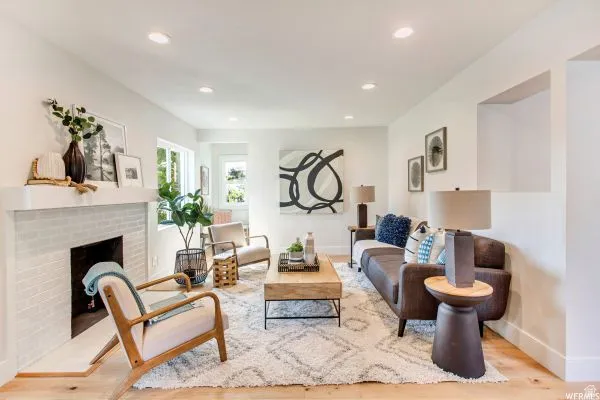 Bright living area featuring a white brick fireplace with a substantial mantel, recessed lighting, and light wood-finish flooring