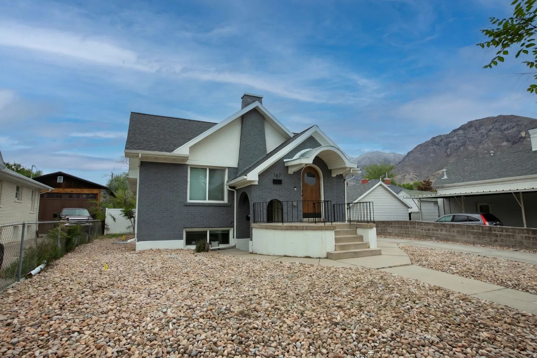 View of front facade with brick siding, a chimney, a shingled roof, and a mountain view