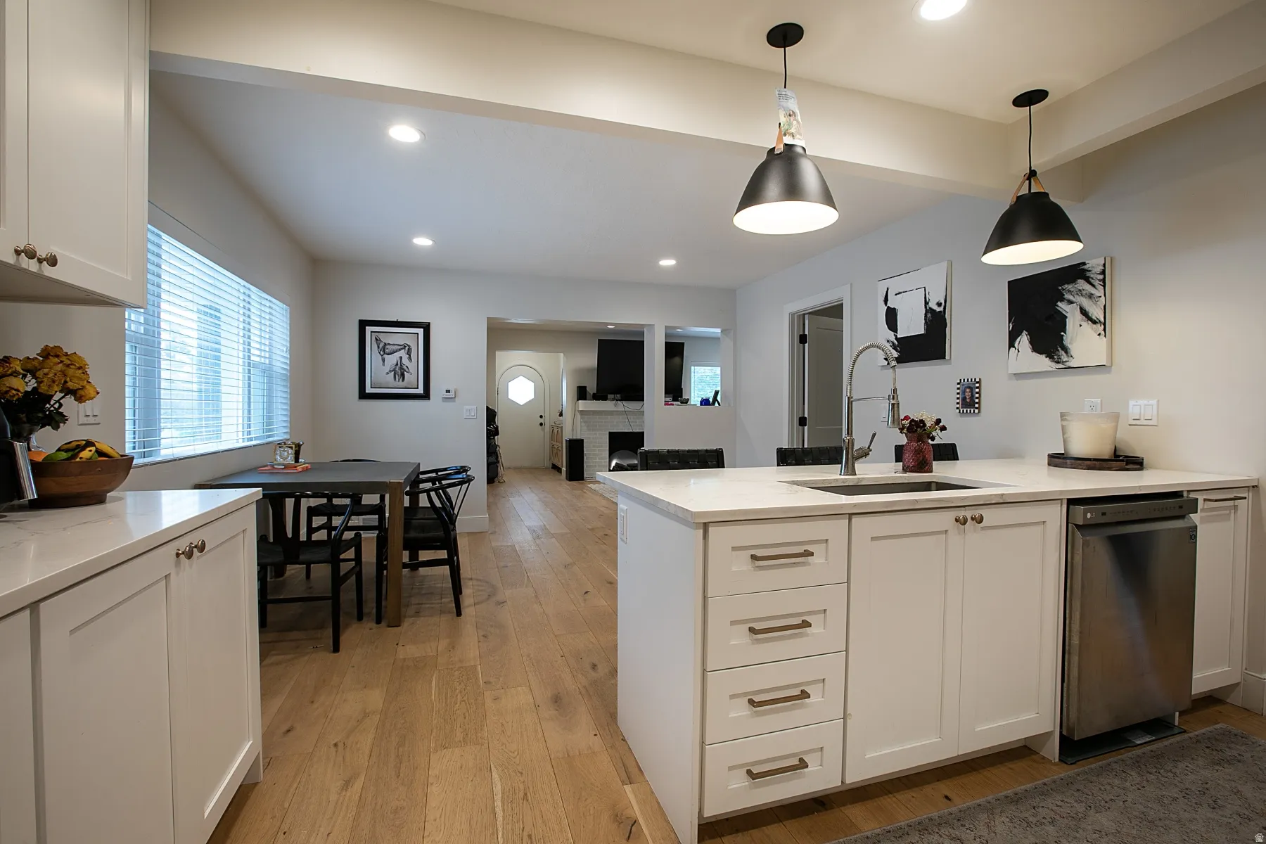 Kitchen featuring white cabinets, a peninsula, light wood-type flooring, light stone countertops, and open floor plan